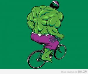 Feminist Hulk wearing tiny purple shorts and riding a tiny bicycle.