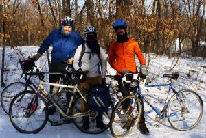 three people with bikes, in a winter forrest