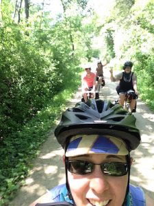 Selfie of rider, more riders waving in the background. on the bike trail.