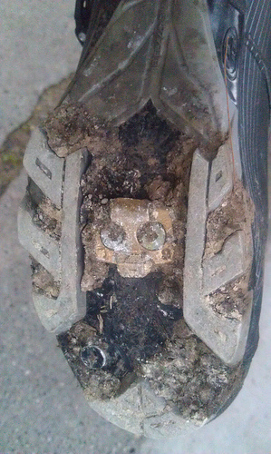 bottom of shoe and cleat with lots of dirt and gravel caked on