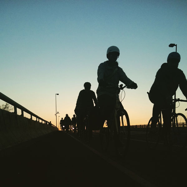 Silohettes of bike riders on a bridge against the setting sun